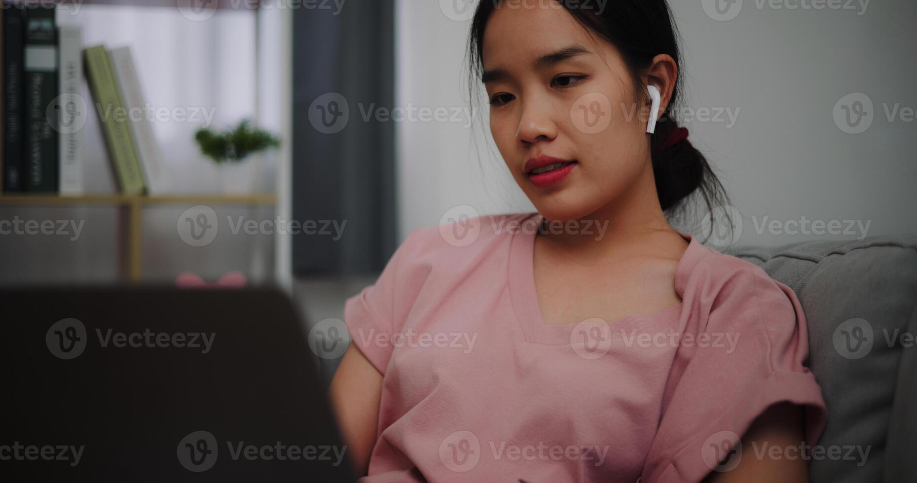 Portrait of Young woman sitting on sofa while working with laptop at home office. photo