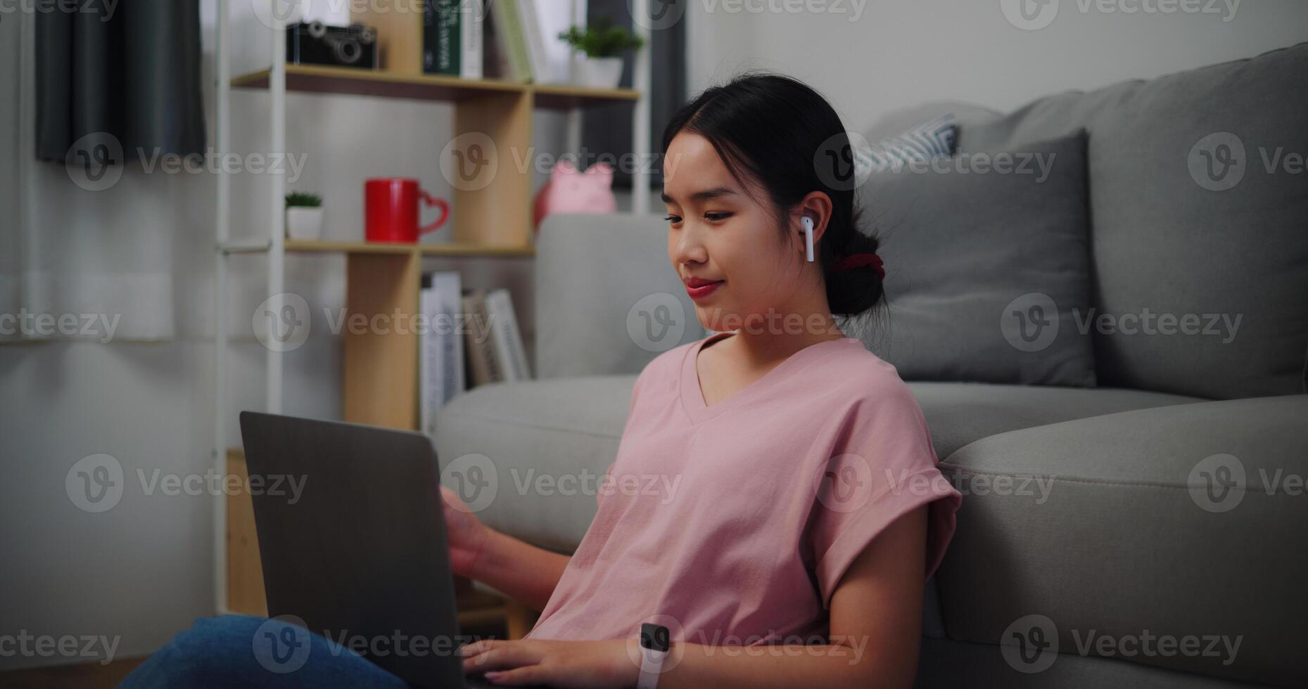 Portrait of Young woman sitting on the floor leaning against a sofa working with a laptop at home office. photo
