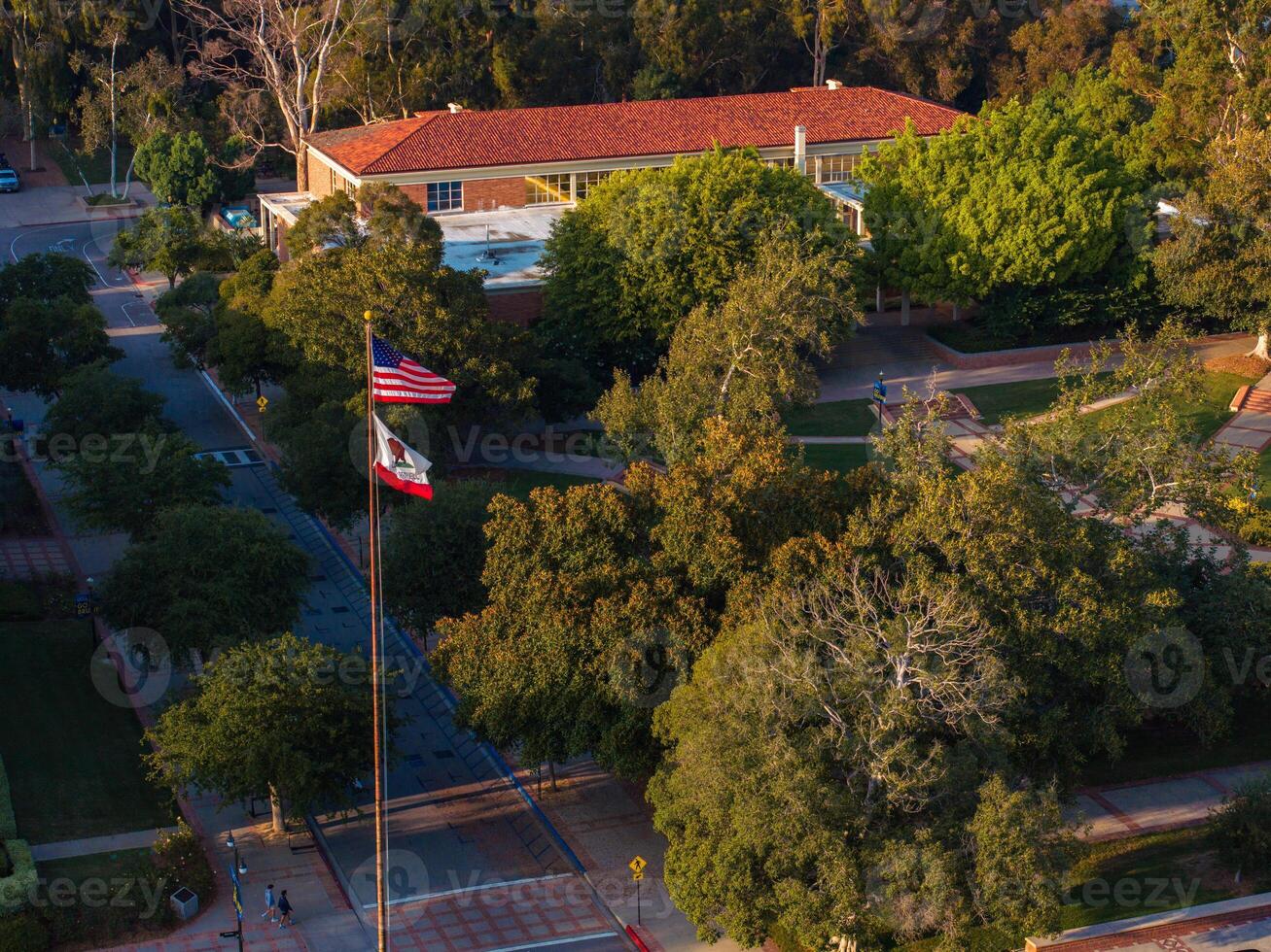 Aerial View of American College Campus with Red-Roofed Building and Flags at Sunrise photo