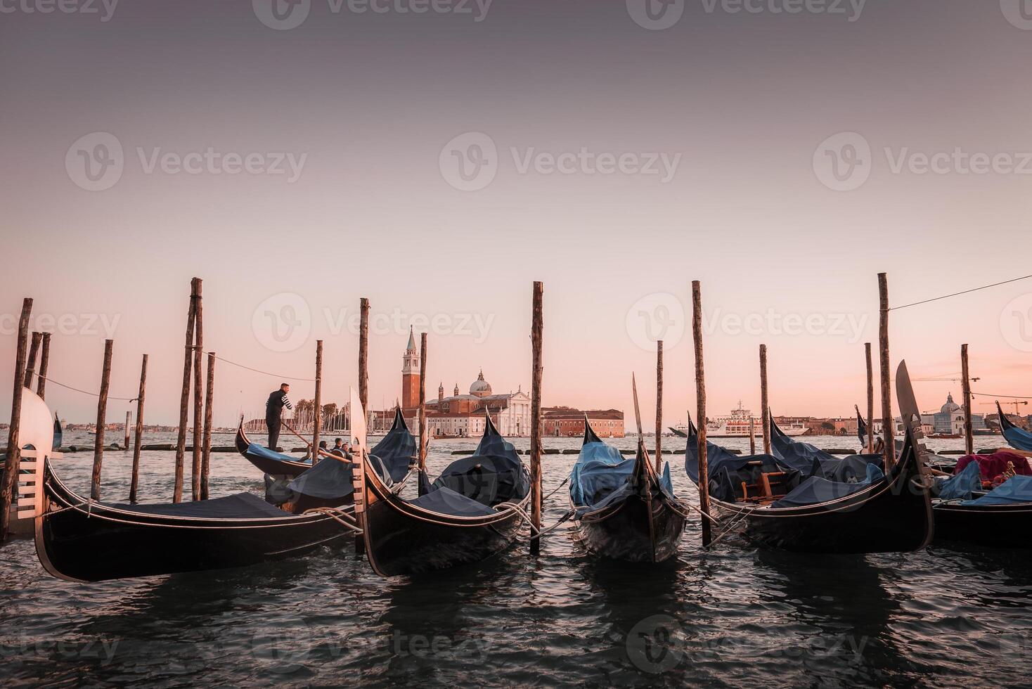 Tranquil sunset scene of gondolas docked in a serene canal, reflecting the soft colors of Venice. photo