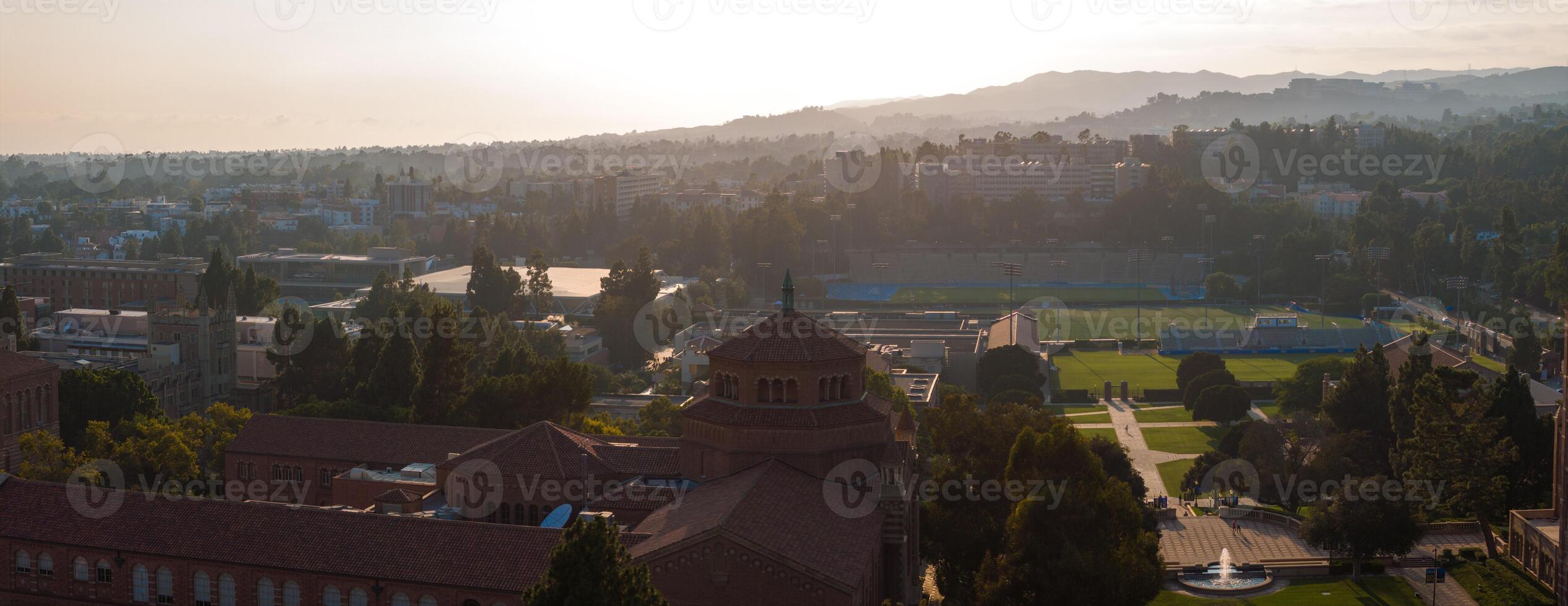 Aerial Sunrise or Sunset View of UCLA Campus with Lush Greenery, Diverse Architecture, and Misty Mountains photo