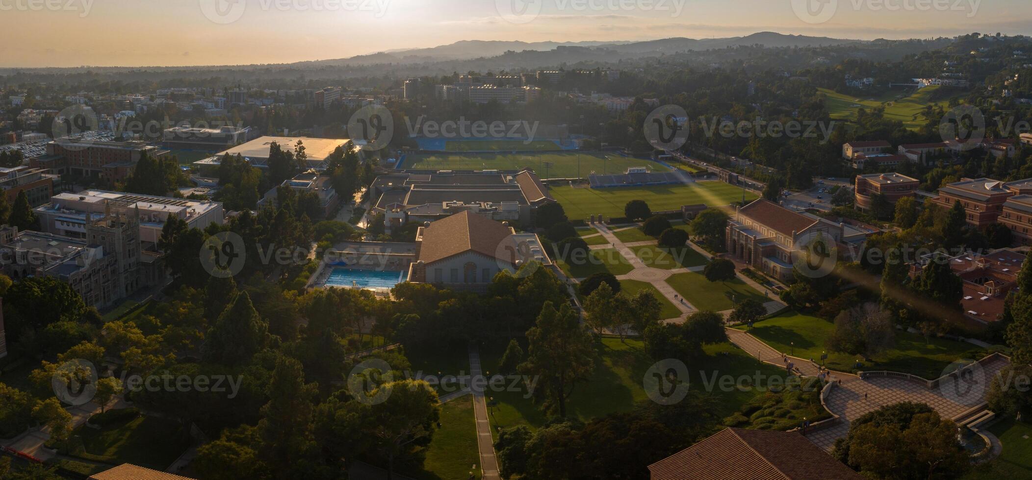 Aerial Sunset View of UCLA Campus with Lush Greenery, Diverse Architecture, and Recreational Facilities photo