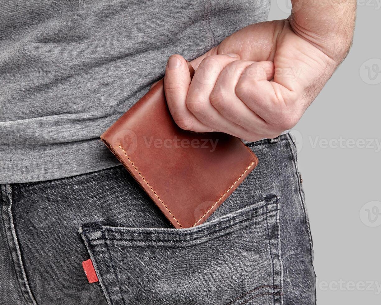 Man inserting personalized leather wallet with embossed initials into pocket photo