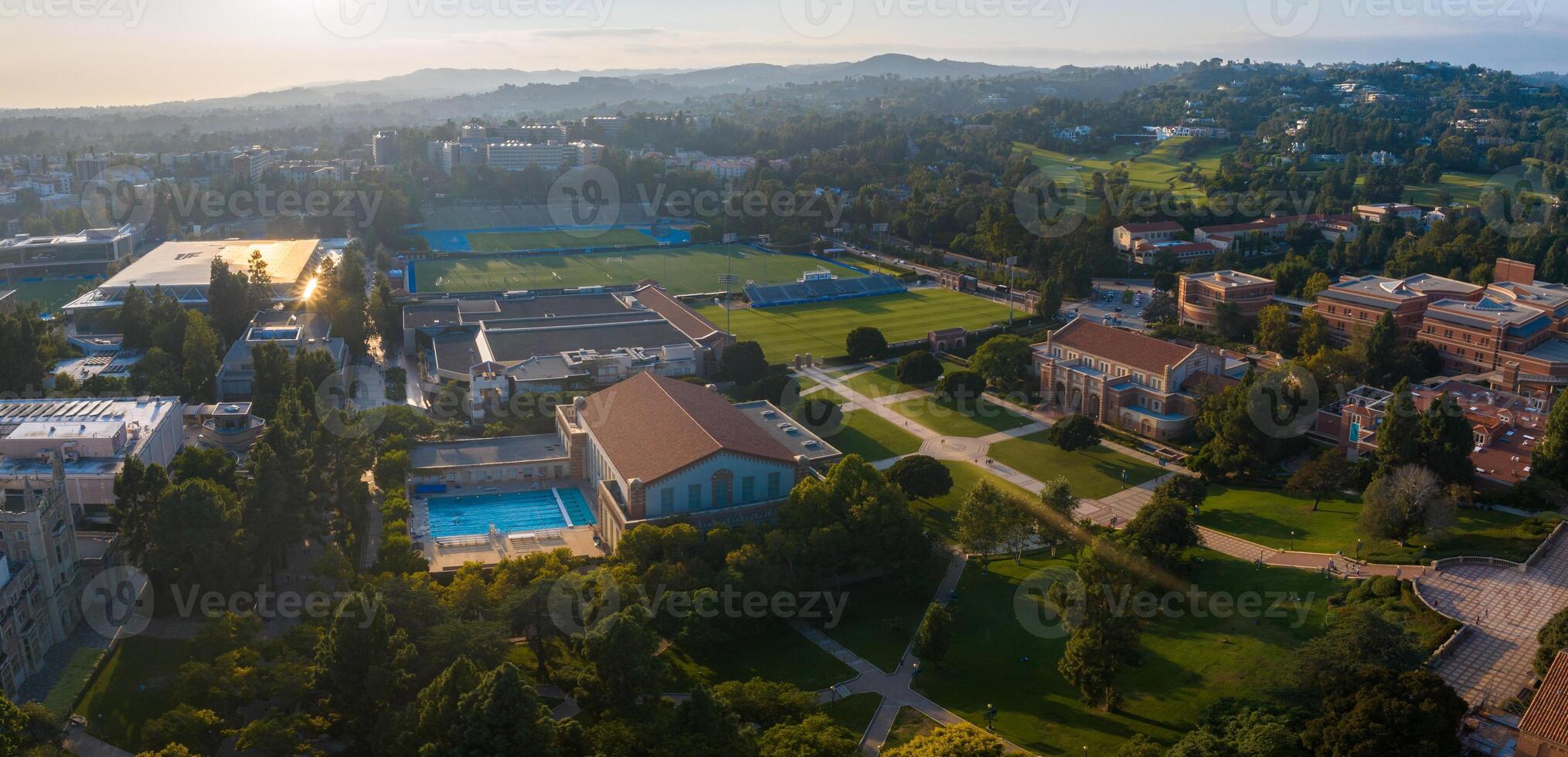 Golden Hour Aerial View of UCLA Campus with Gothic Architecture, Lush Greenery, and Swimming Pool photo