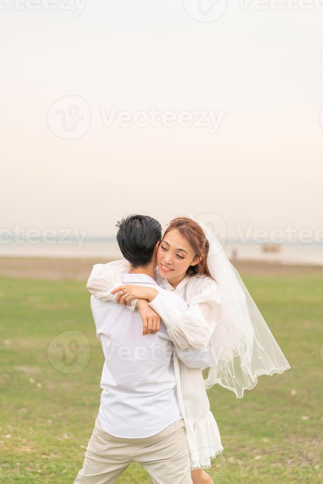 Happy young Asian couple in bride and groom clothing photo