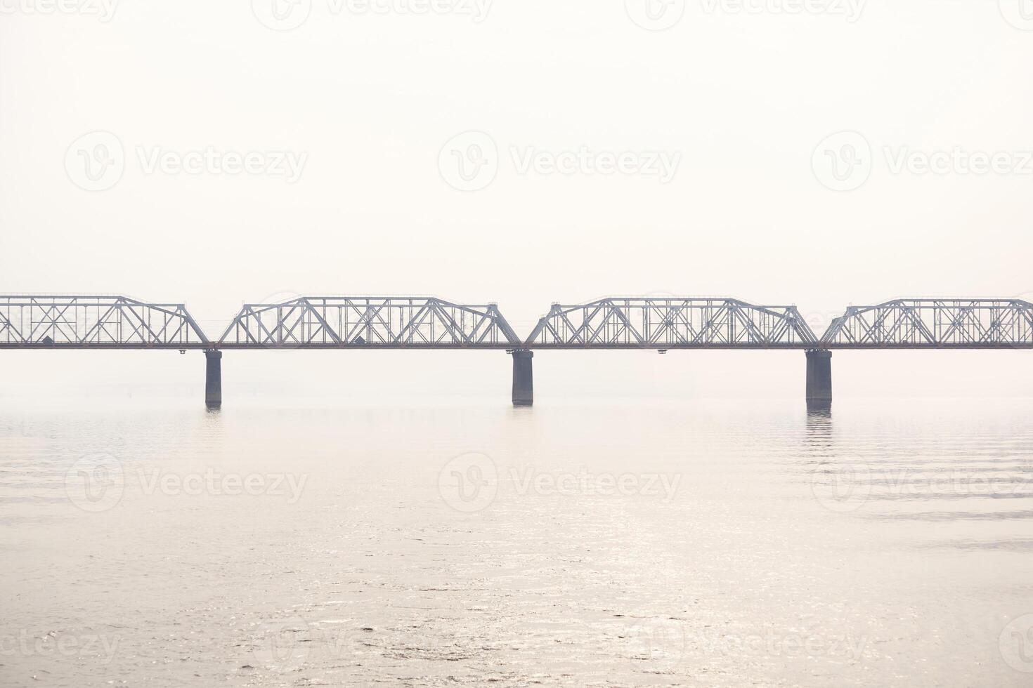 railroad truss bridge over a wide river in fog photo