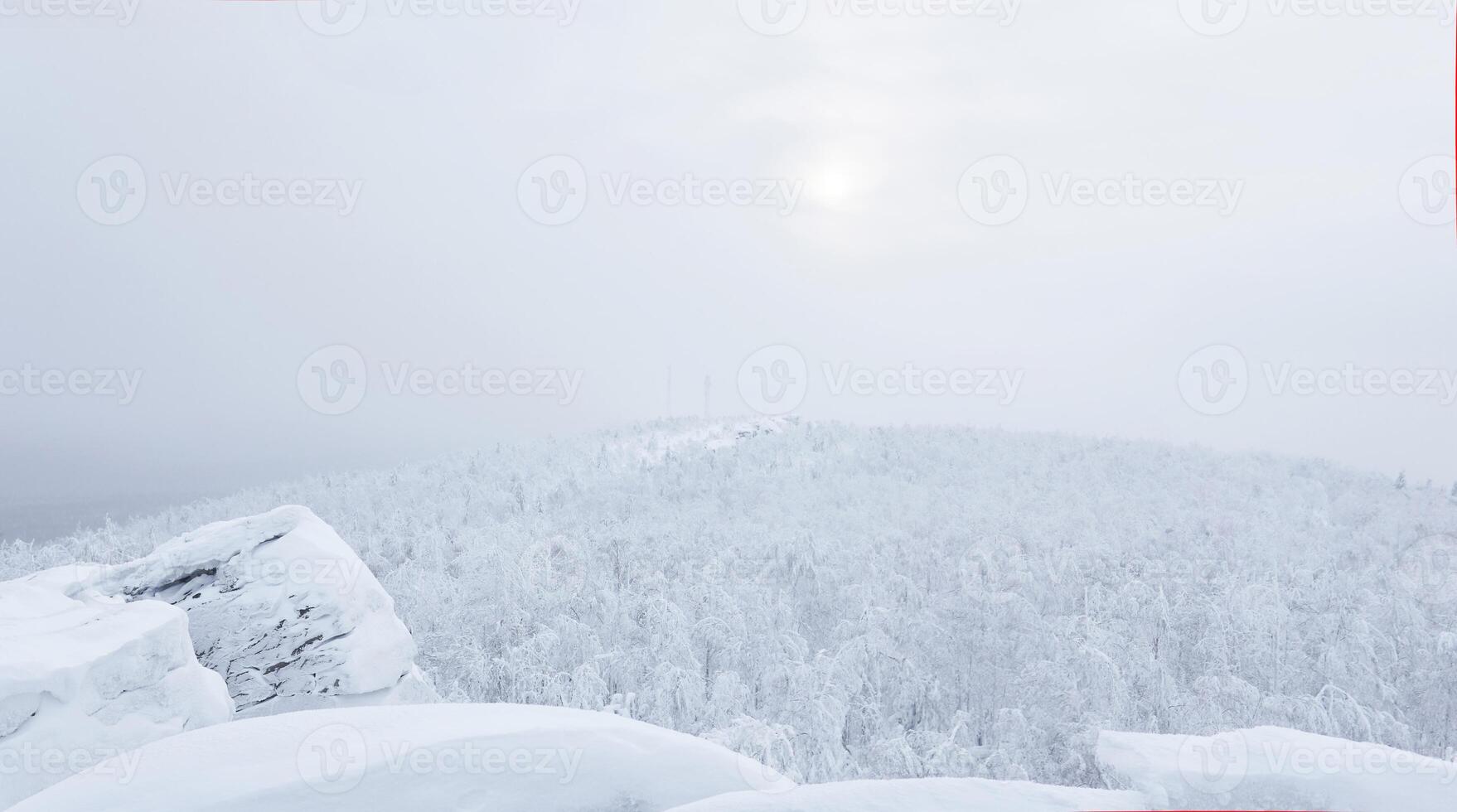 winter view from the top of the mountain to the snowy wooded hills in frosty fog, cell towers are visible in the distance photo