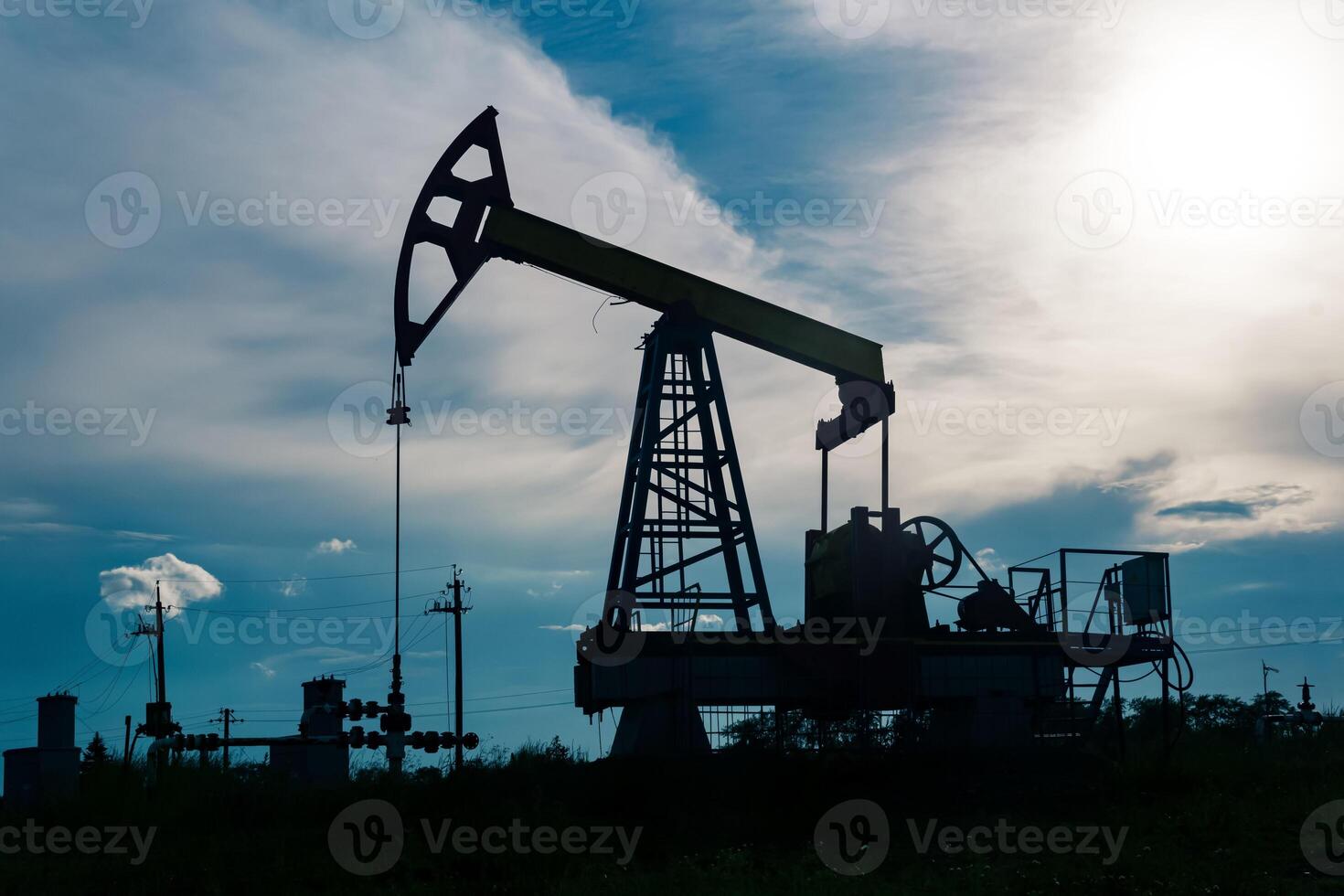 silhouette of a pumpjack on an oil well against the background of sky photo