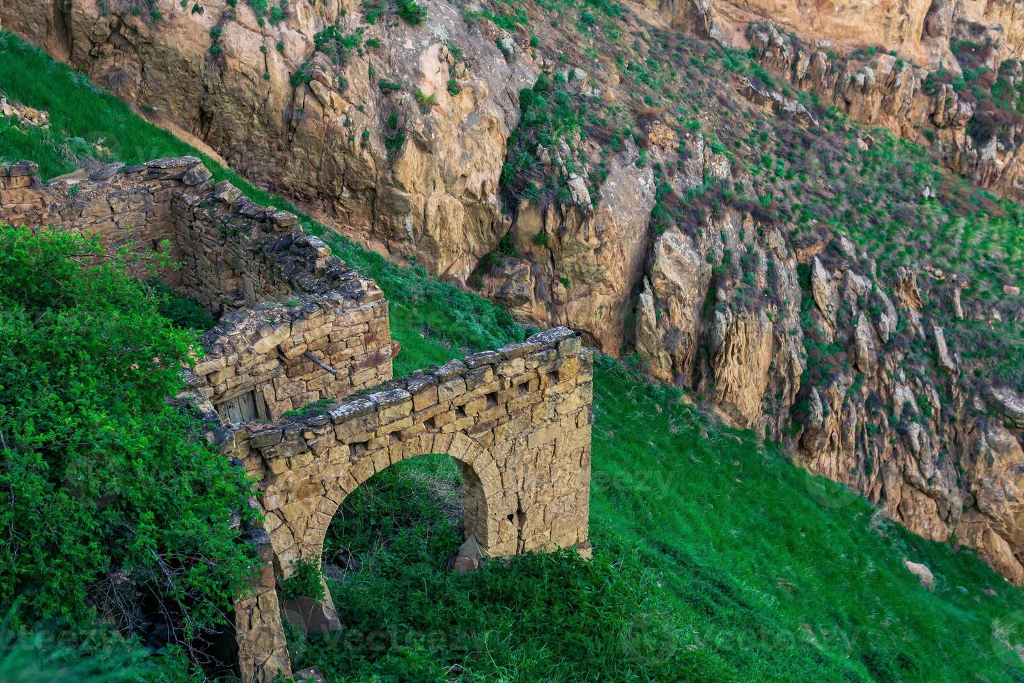 ruins of stone walls on a steep mountain slope in an abandoned highlanders village Gamsutl in Dagestan photo