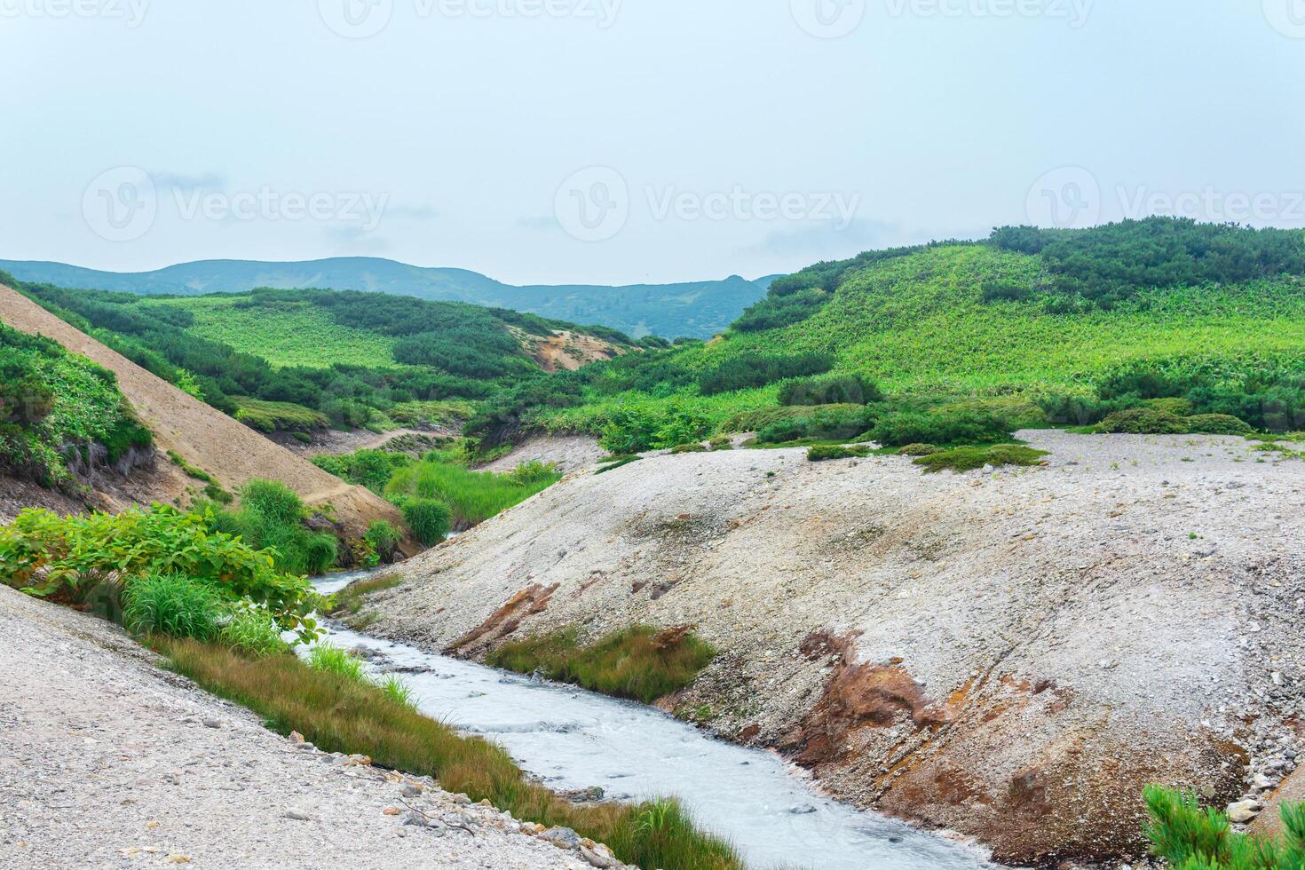 geothermal mineralised stream among the banks of volcanic ash and tephra in the caldera of Golovnin volcano, Kunashir island photo