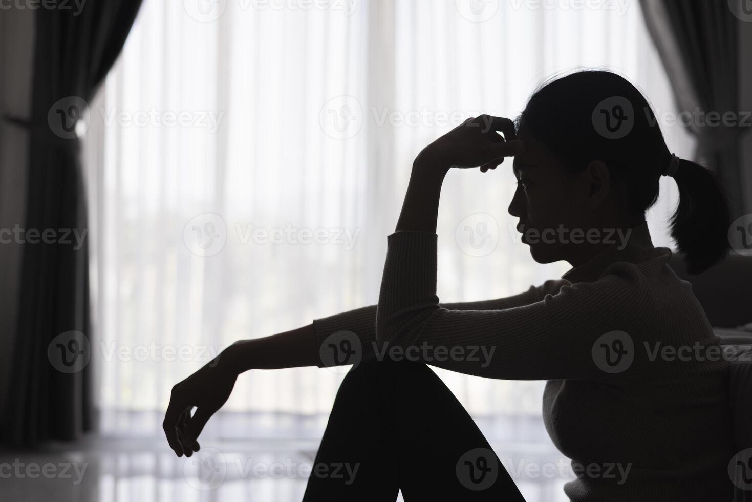 Silhouette of a person suffering from depression in the house, Depressed woman sitting alone on the Sofa feel stress, sad and worried in the dark room. person are stressed. photo