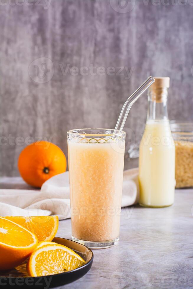 Vegetarian smoothie made from rice milk and orange in a glass on the table vertical view photo