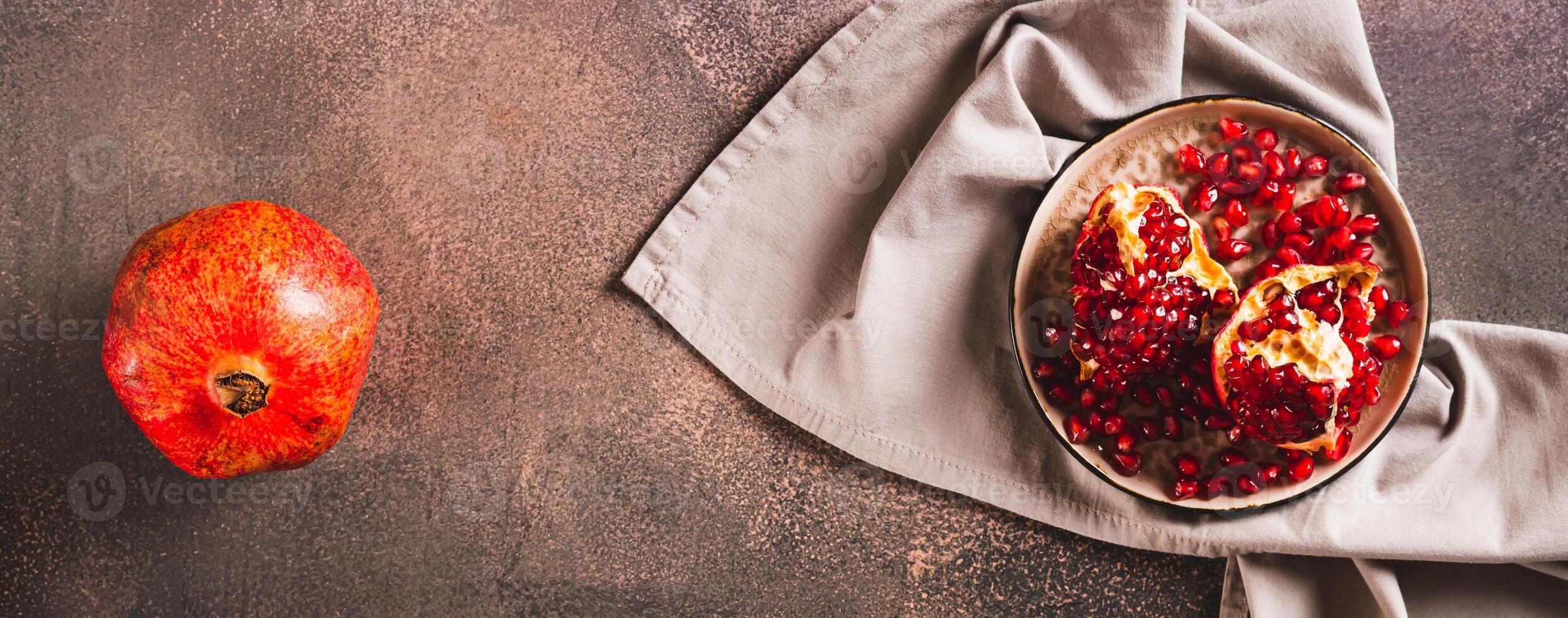 Fresh tasty pomegranate divided into pieces on a plate on the table top view web banner photo