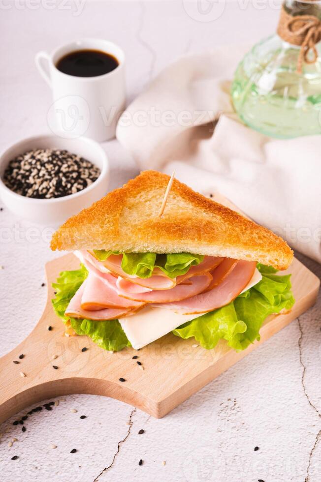 Toast sandwich with ham, cheese and herbs on a wooden board on the table vertical view photo