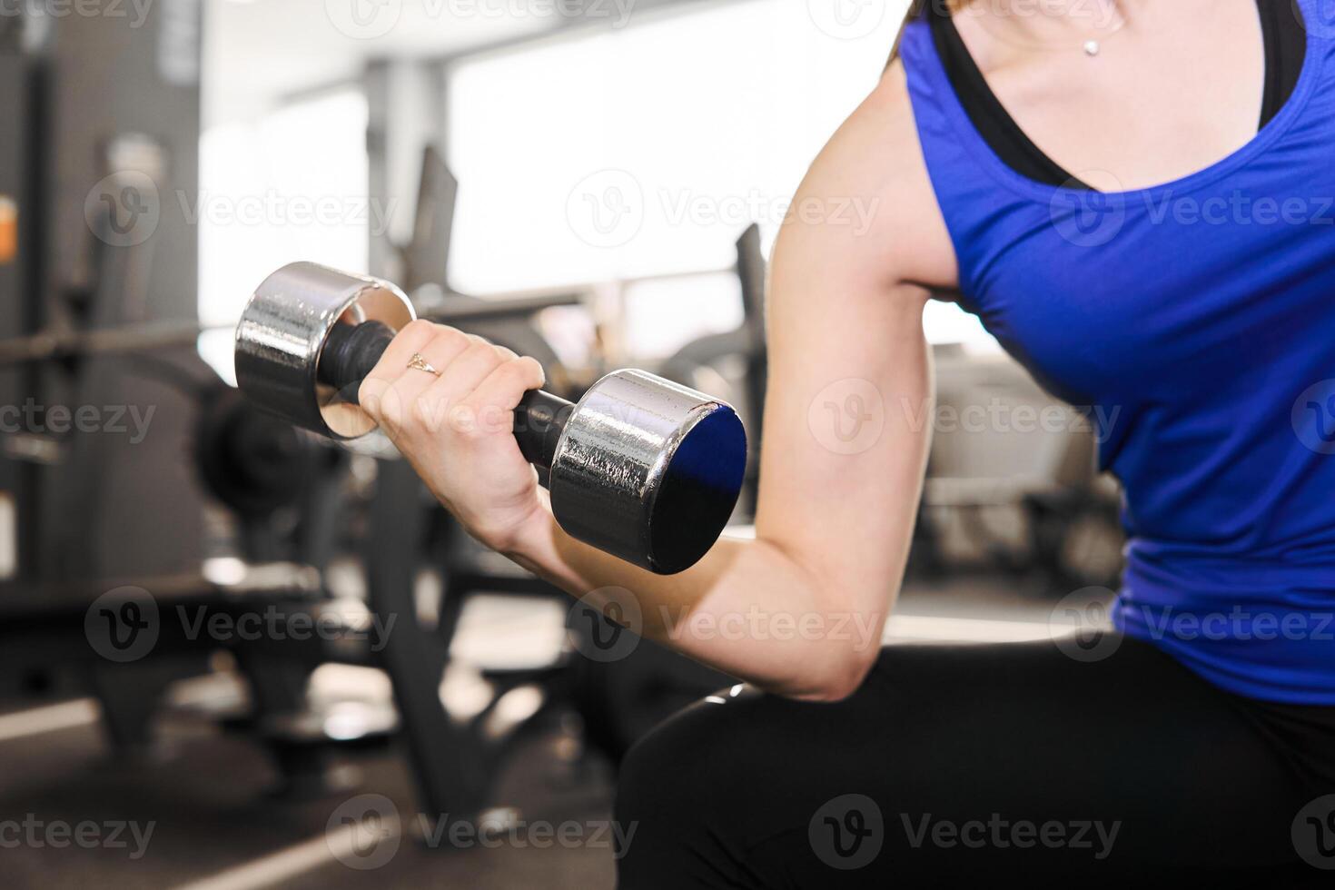 hand of a woman performing exercise with dumbbell in the gym photo