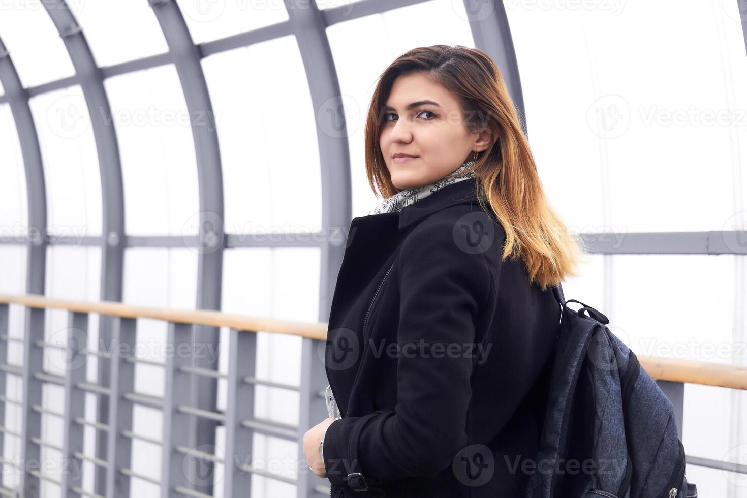 young beautiful woman looks back walking along the covered overpass photo