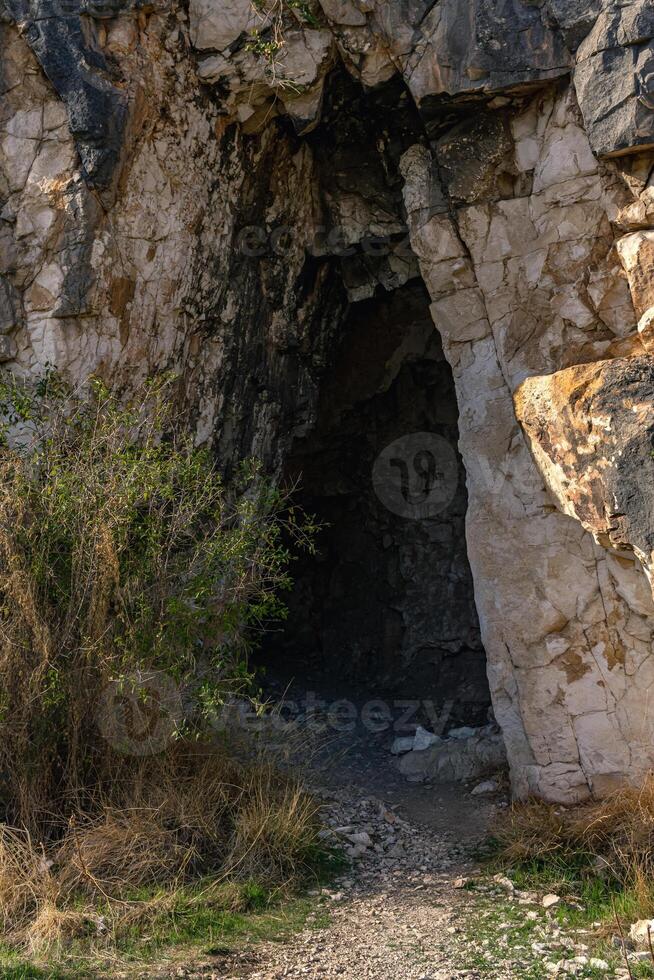 entrance to an ancient rock tomb carved into the mountainside photo