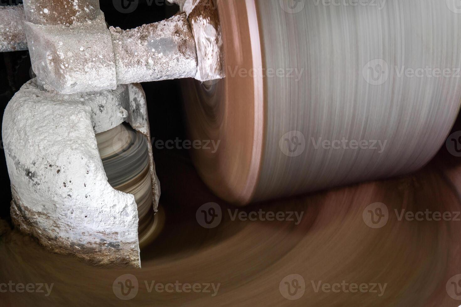 millstone of industrial melanger grind cocoa in the process of making chocolate, blurry in motion photo