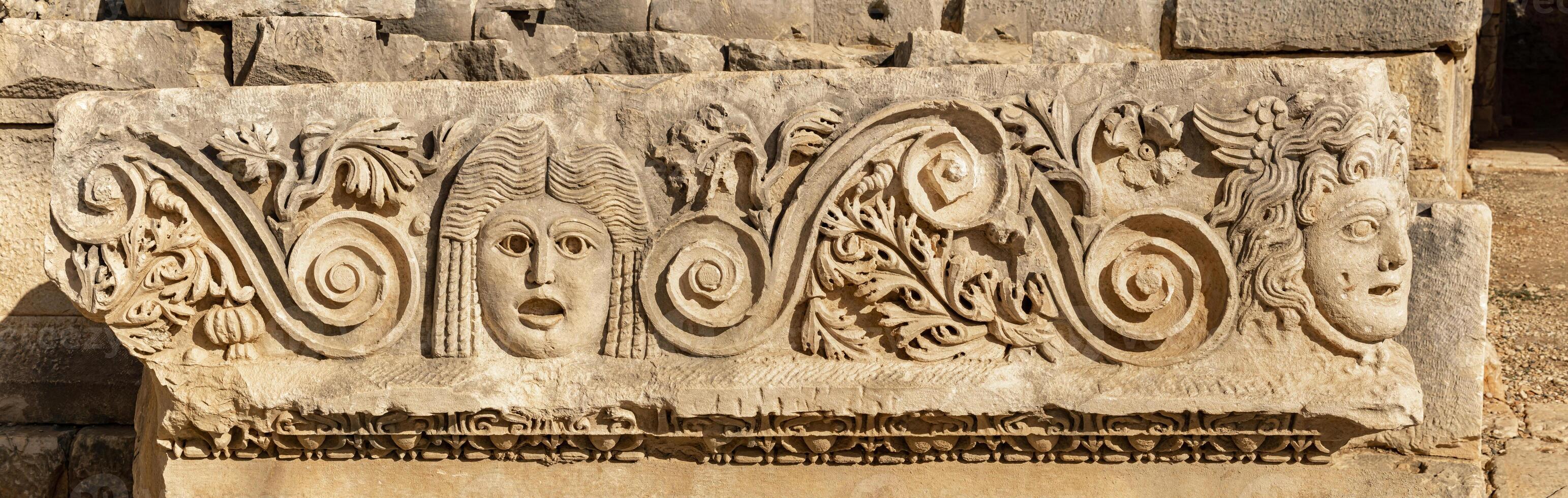antiguo friso con tallado en piedra caras en el restos de el antiguo ciudad de mira, Turquía foto