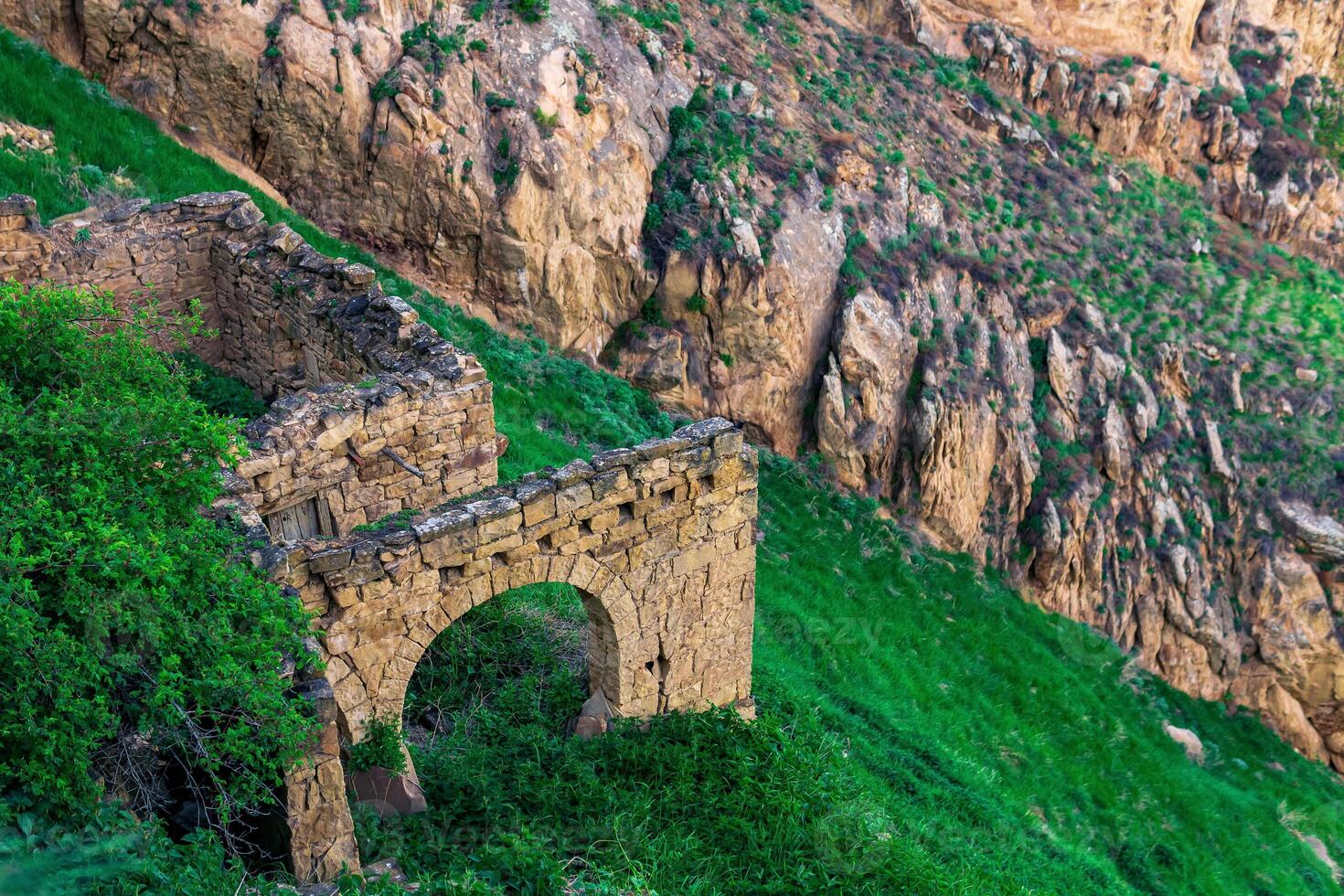 ruins of stone walls on a steep mountain slope in an abandoned highlanders village Gamsutl in Dagestan photo