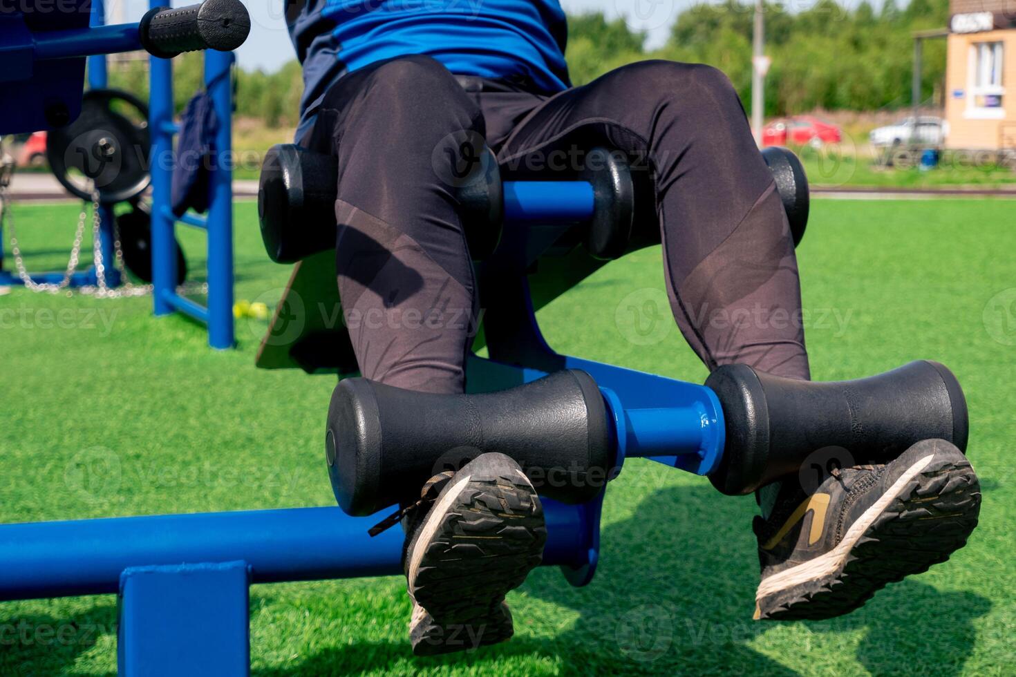 legs of a person, shakes her press using an outdoor exercise machine abdominal bench photo