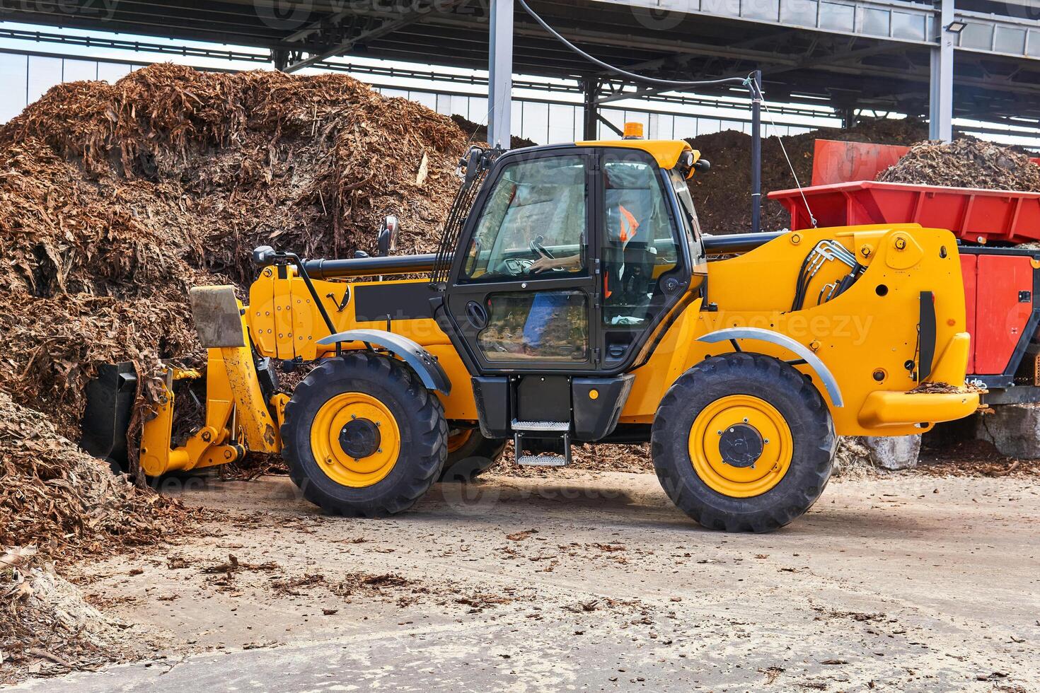 bucket loader loads tree bark into an industrial woodchipper photo