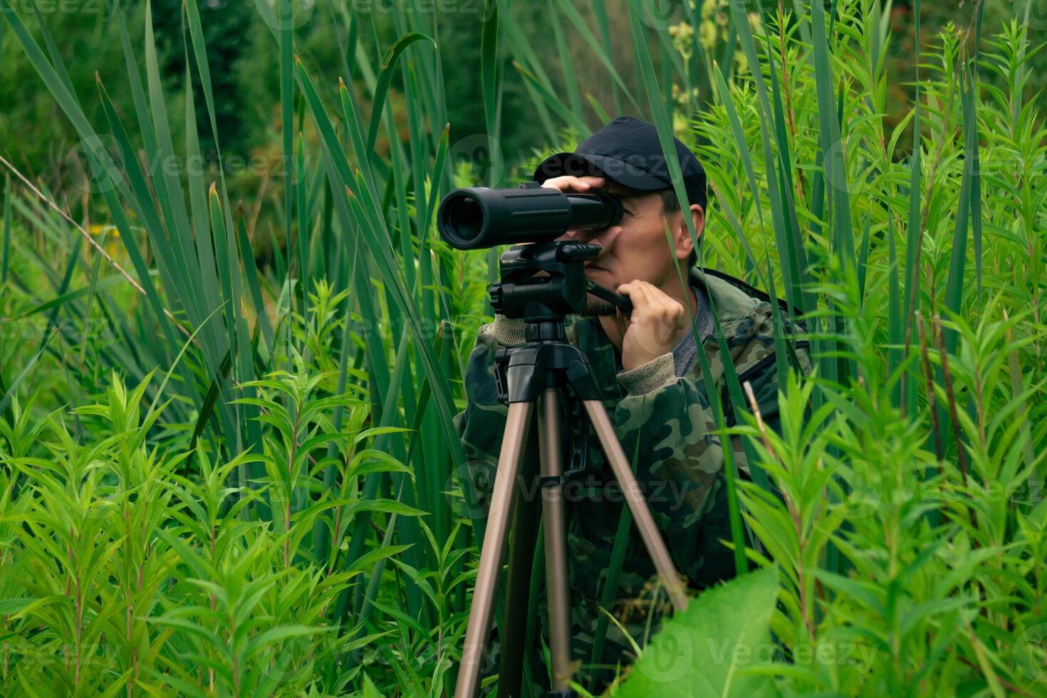 male ornitologist makes observations in the wild with a spotting scope photo