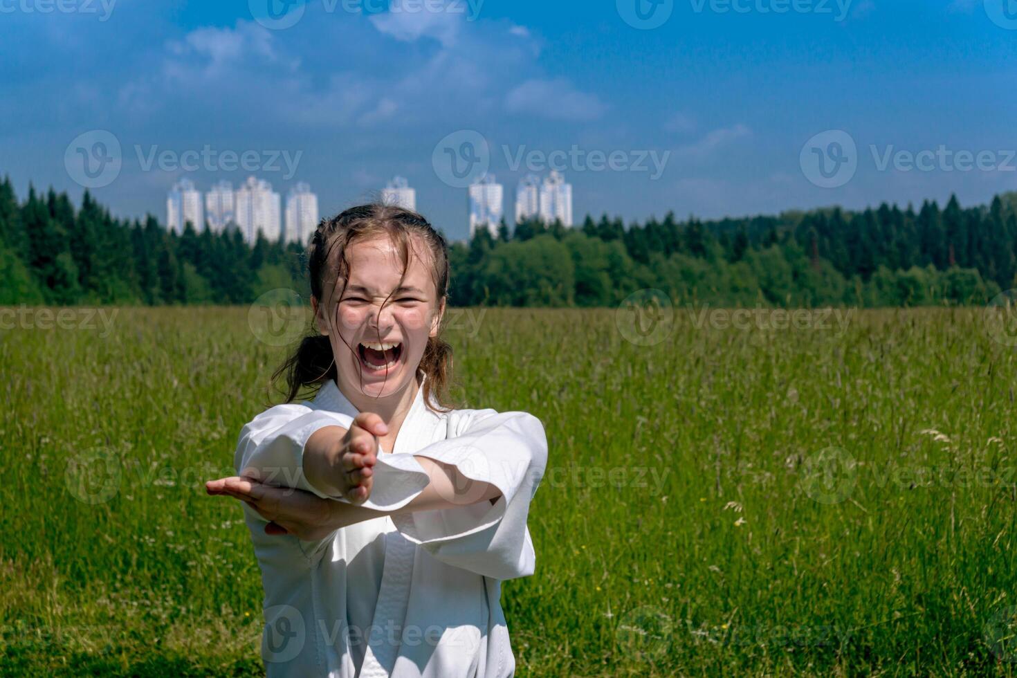 Adolescente niña formación kárate kata al aire libre, realiza nukita tsuki Huelga con kiai gritar foto