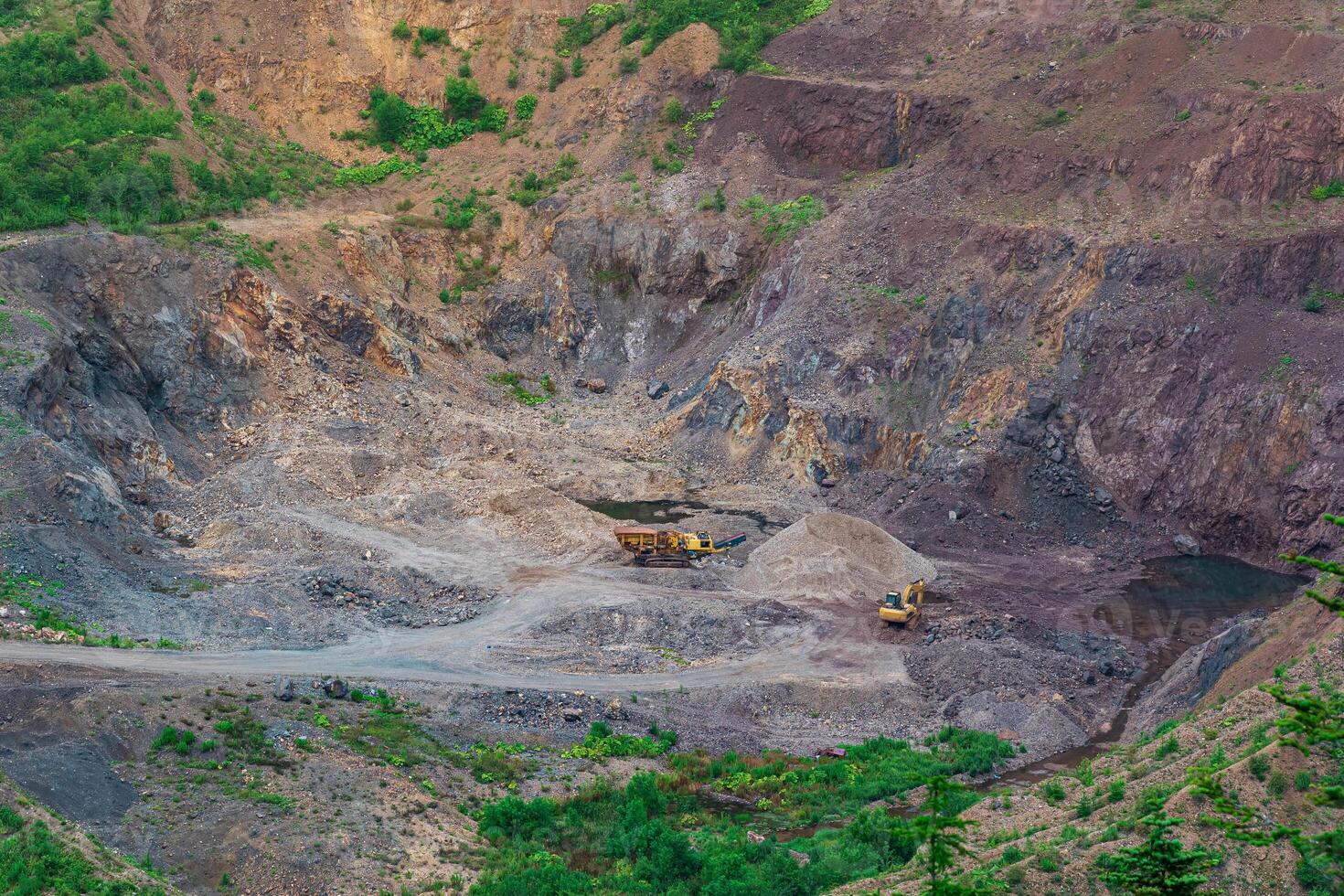 small quarry with mining machinery in mountainous area photo