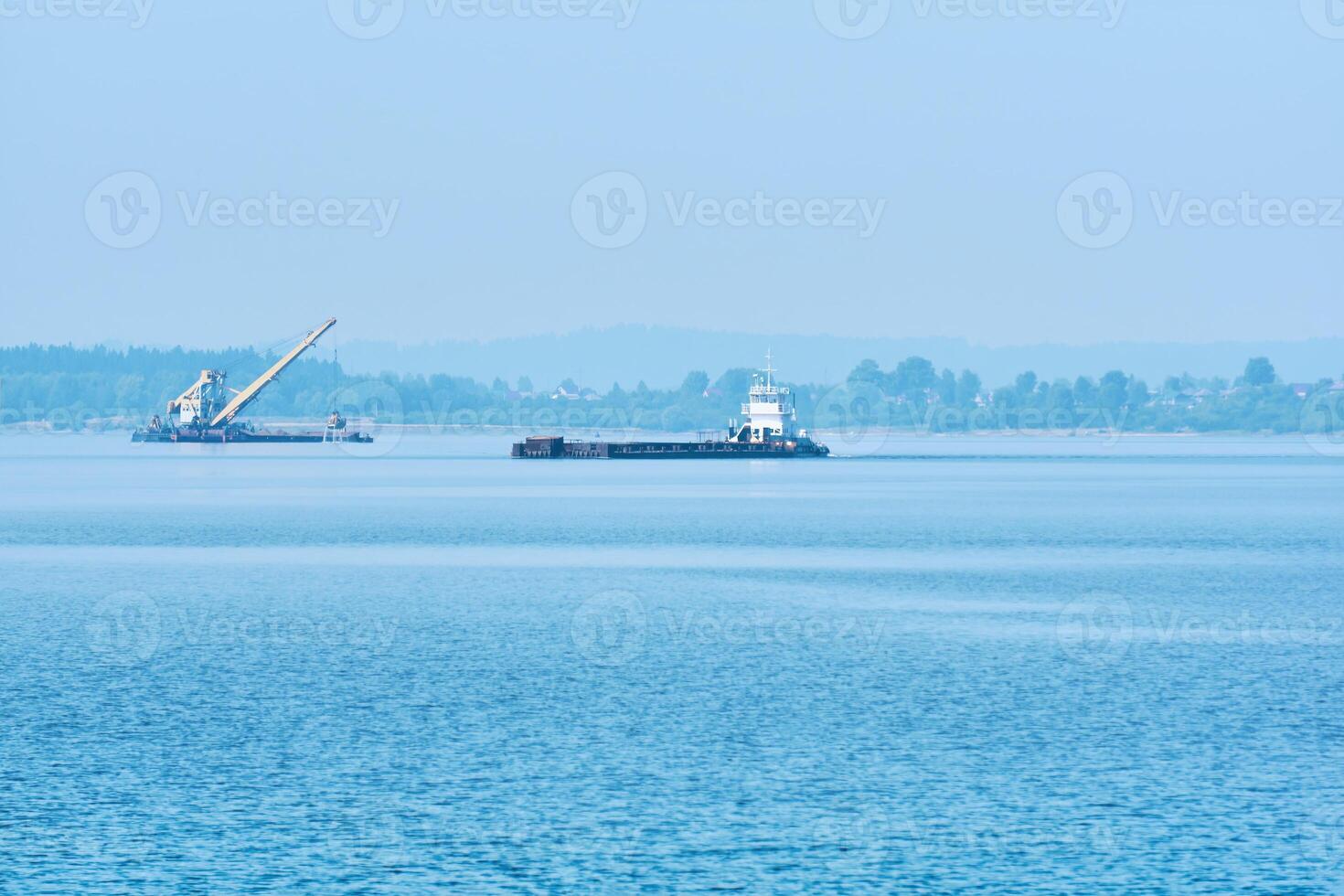 foggy river water landscape with cargo barge and dredger in the background photo