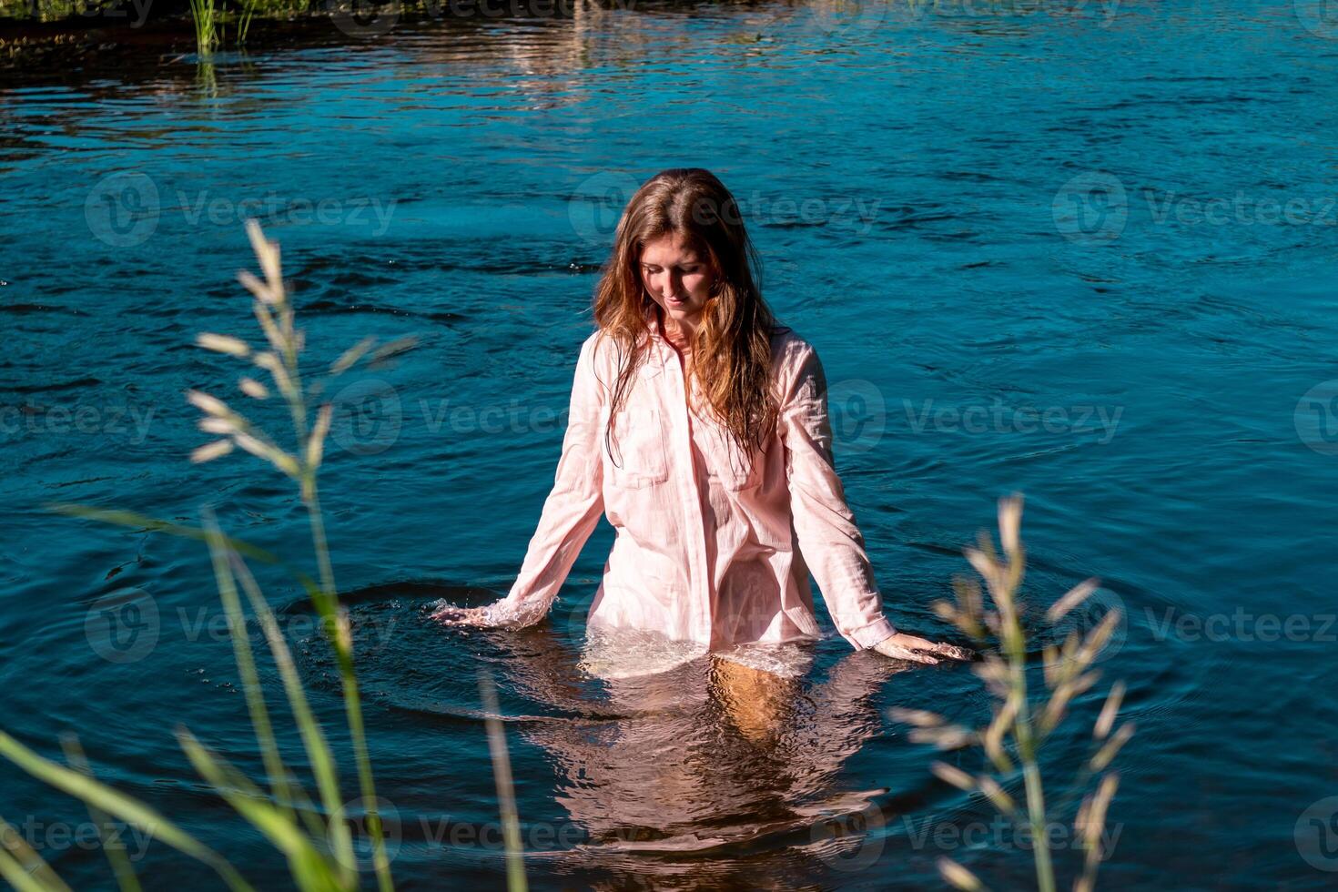 joven mujer se baña en el río disfrutando el frio agua foto