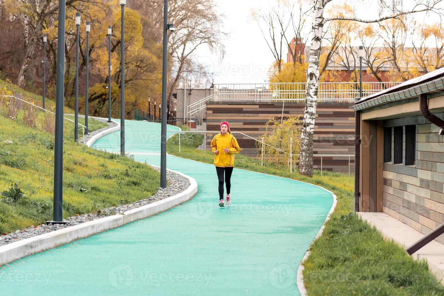 young woman jogging on all-weather running track in an urban environment photo