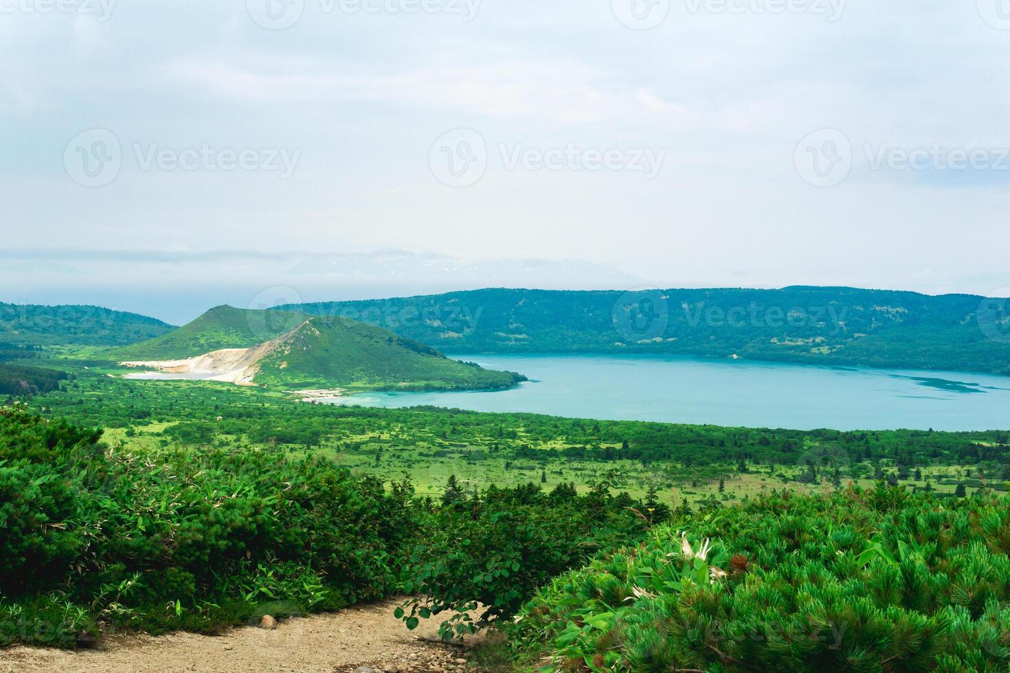 natural landscape of Kunashir island, view of the Golovnin volcano caldera with hot lakes and a path through the thickets of sasa and dwarf pines on a foreground photo