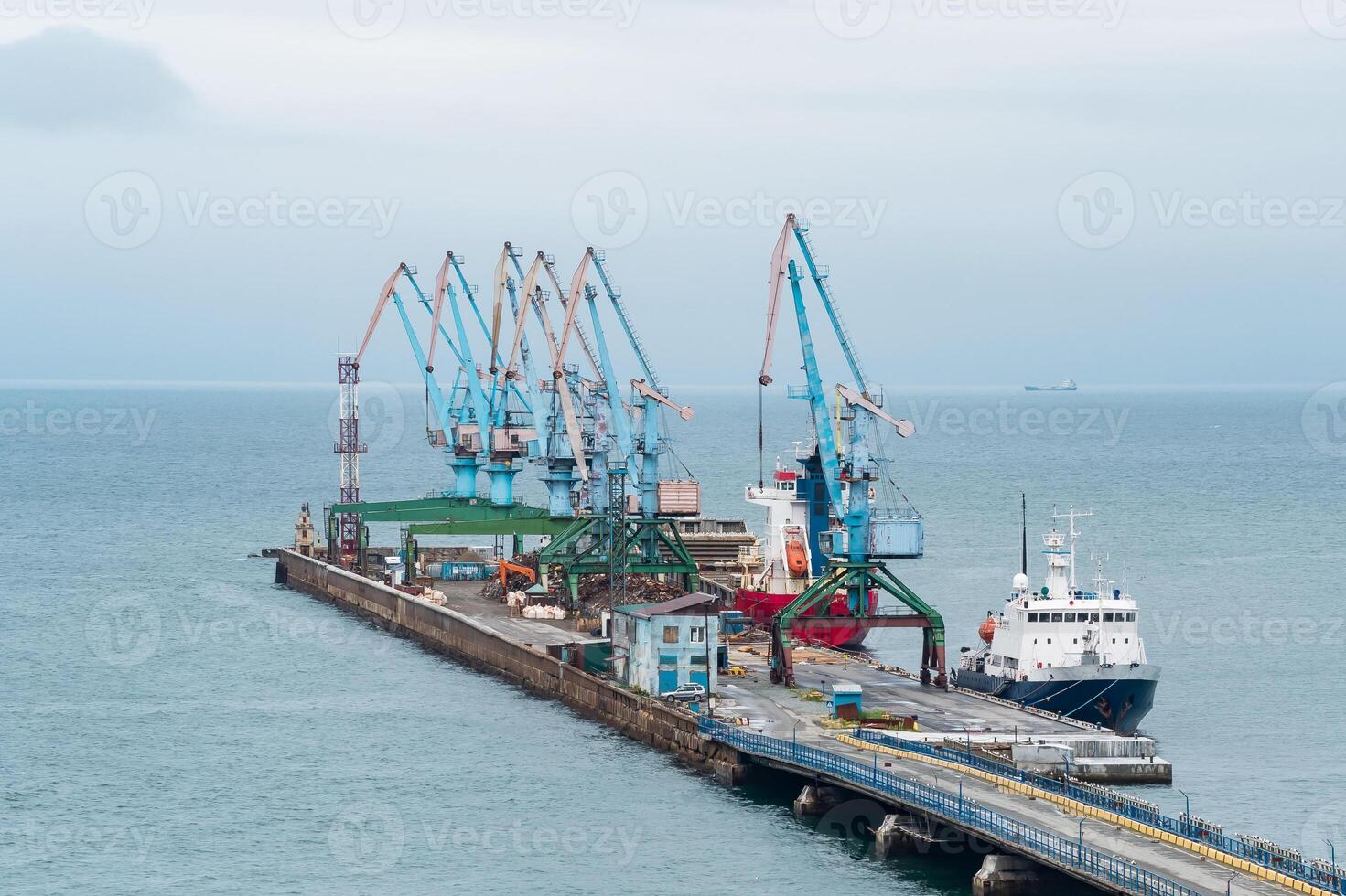 carga atracar con Puerto grúas y amarrado buques en contra el fondo de el abierto mar foto