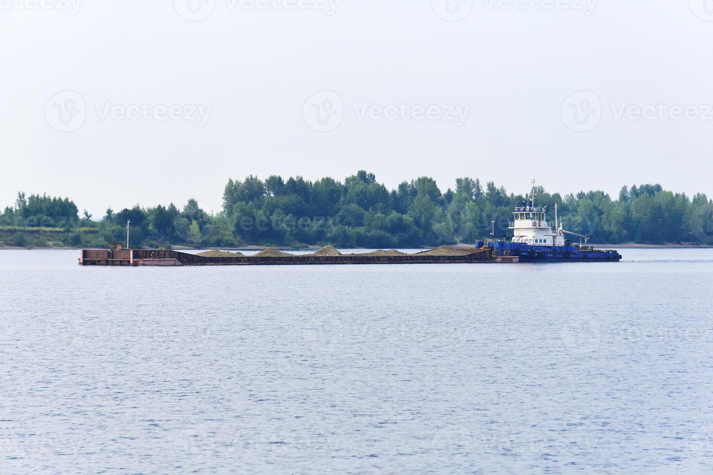 pusher tug pushes dry bulk cargo barge with sand on the river photo