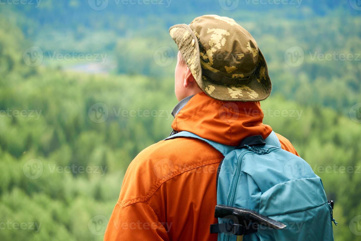 male traveler looking into the distance against the backdrop of a wooded mountain landscape photo
