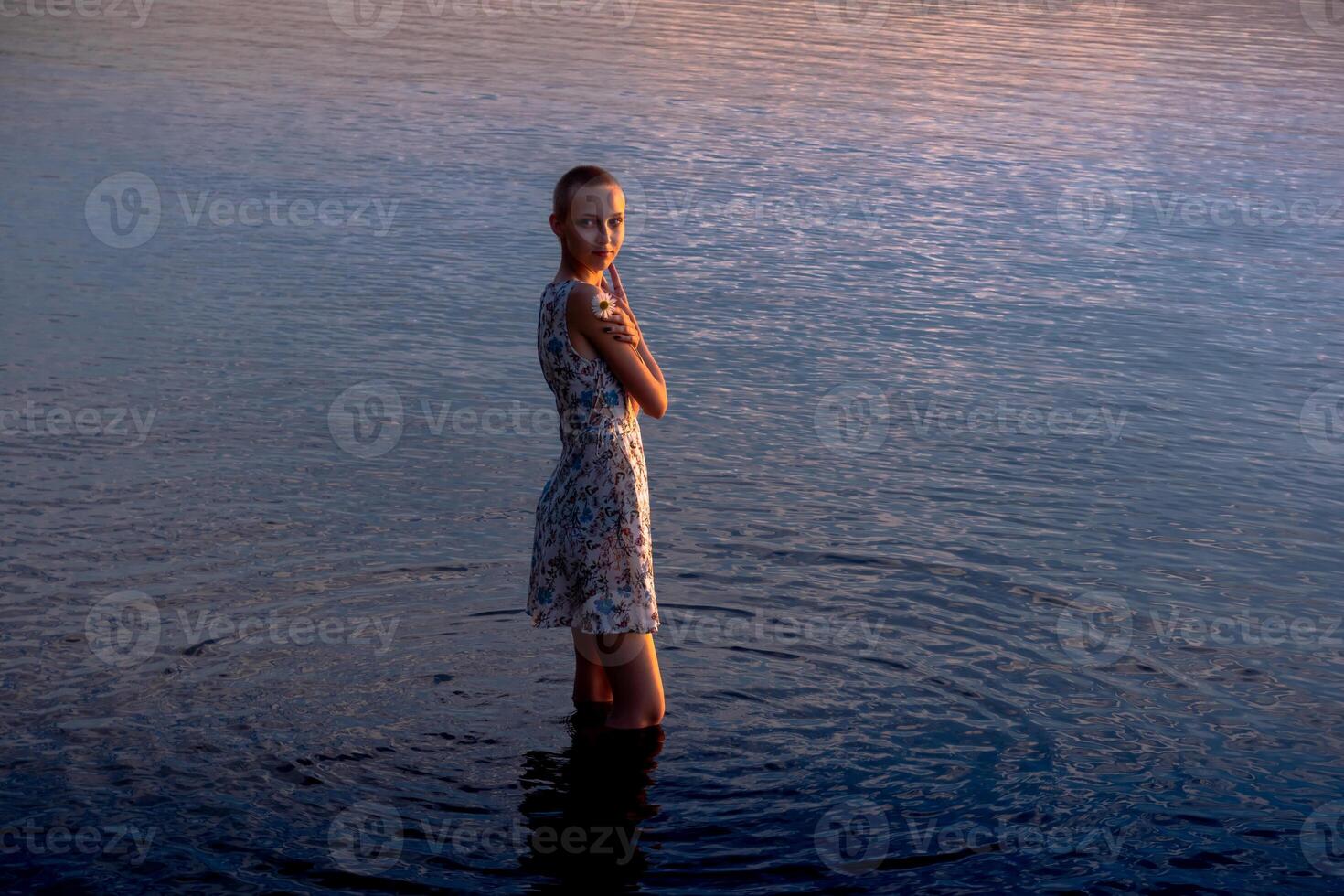 adolescente niña en un vestir por el mar entra el agua foto
