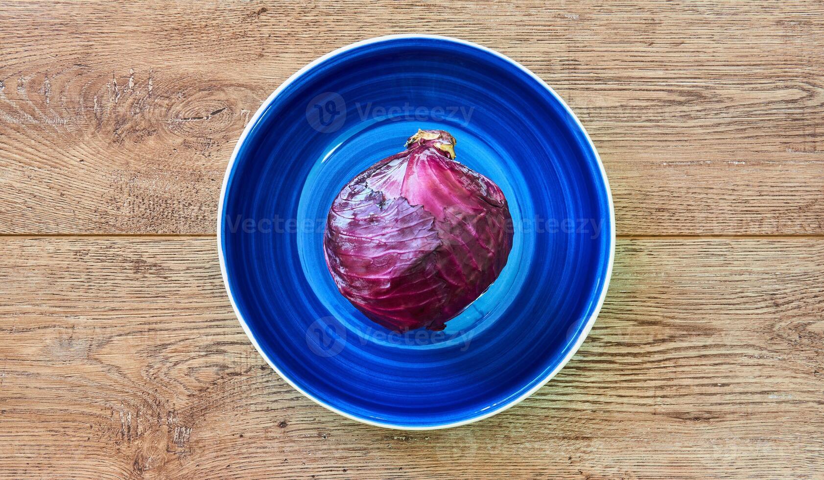 purple head of red cabbage on a blue plate on a wooden tabletop photo