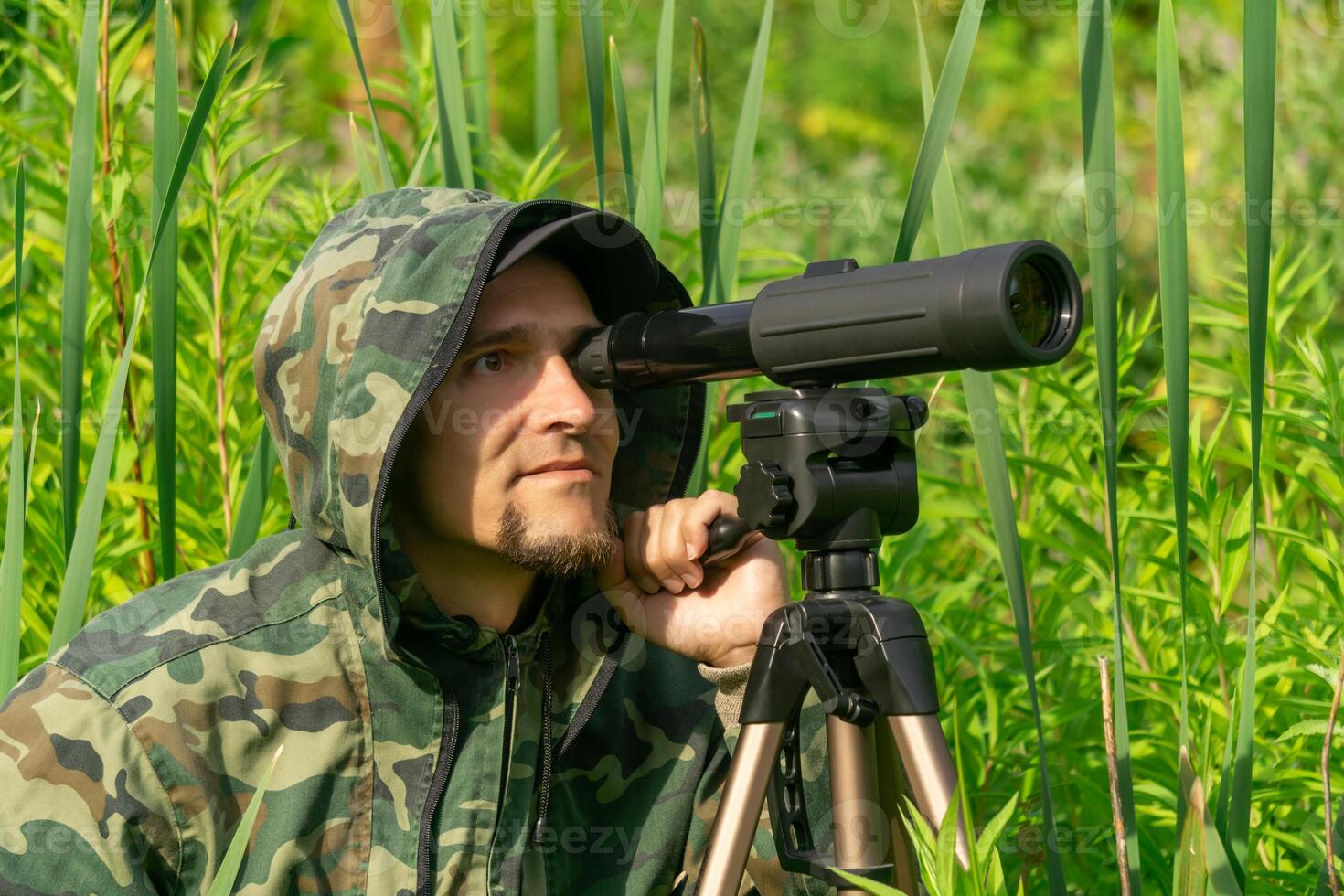 man ornitologist makes observations in the wild with a spotting scope photo