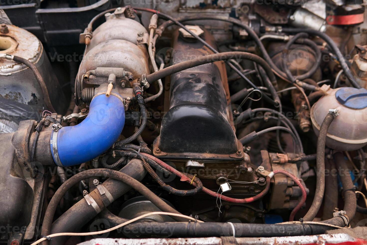old dirty car engine with numerous modifications under the hood photo