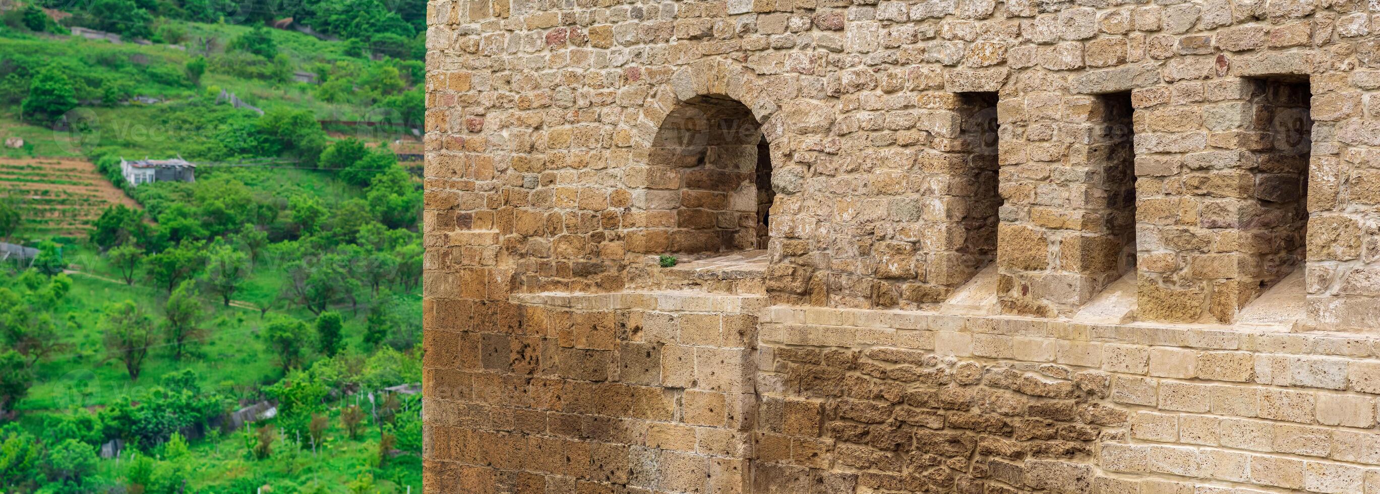 fragment of the wall of a medieval castle, behind which the faubourgs are visible, Naryn-Kala citadel in Derbent photo