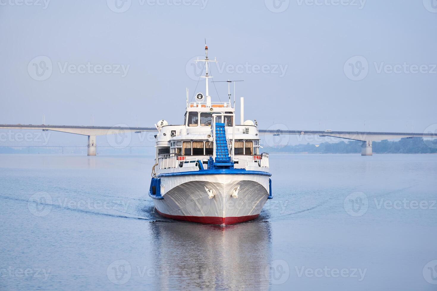 small passenger motorship on the river and road bridge in the morning haze in the background photo