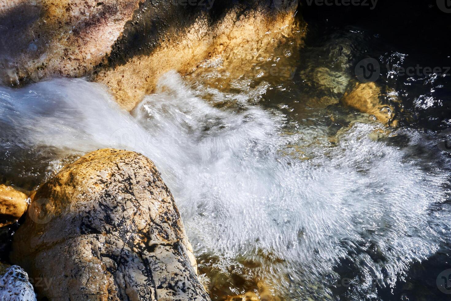 fast foamy mountain stream among rocks blurred in motion photo