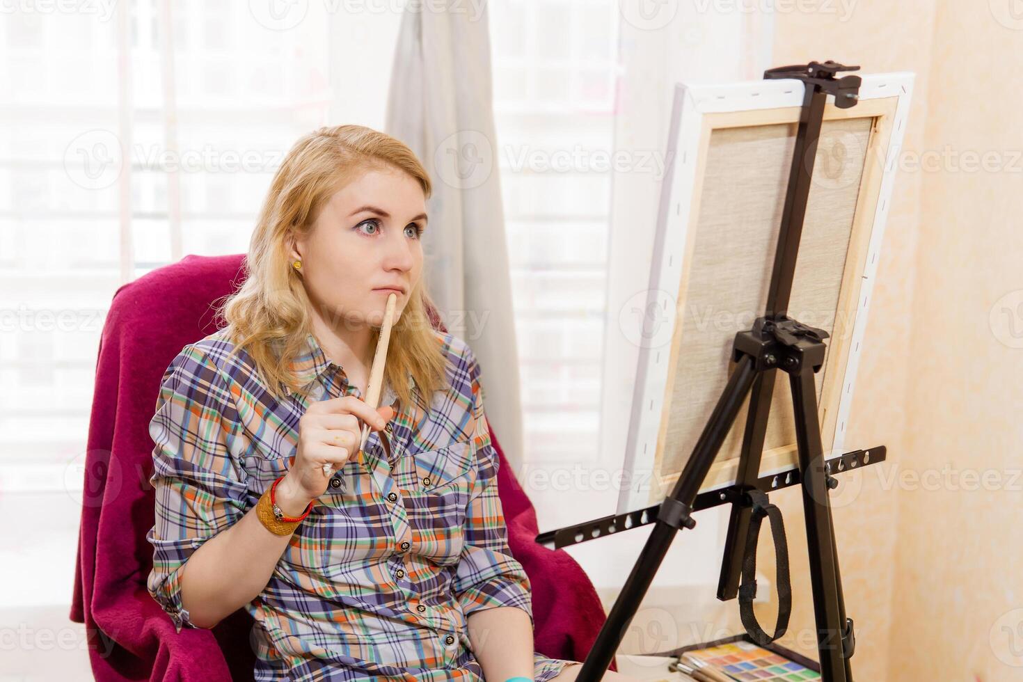 female artist looks thoughtfully at the canvas photo