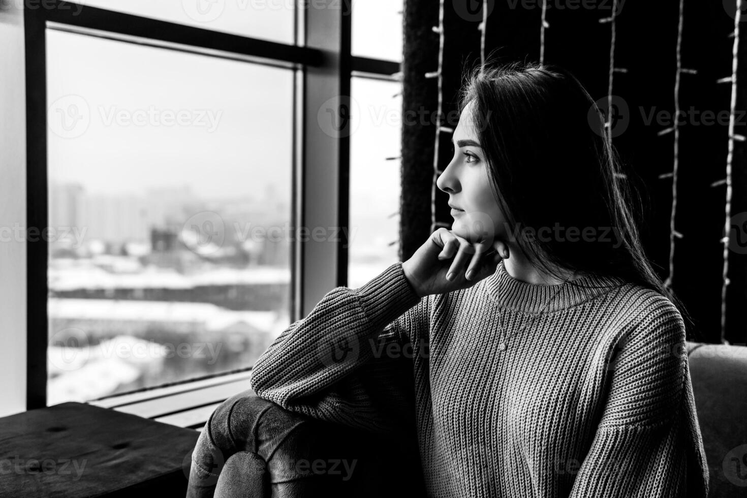 young woman looking thoughtfully out the window on a winter day photo