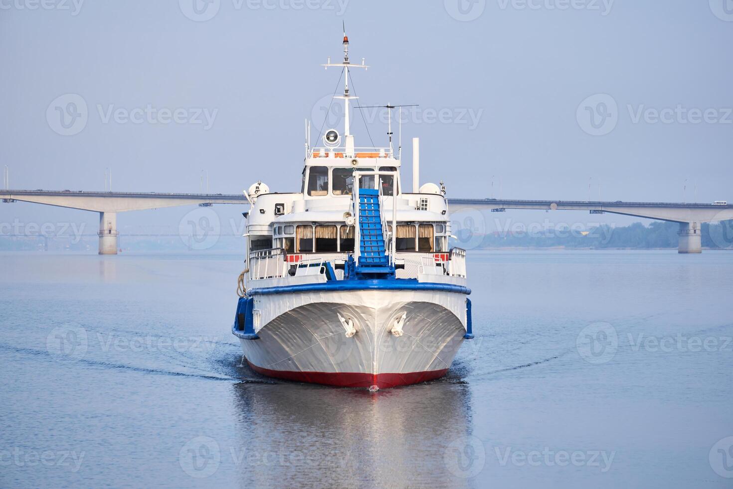 small passenger ship on the river and road bridge in the morning haze in the background photo