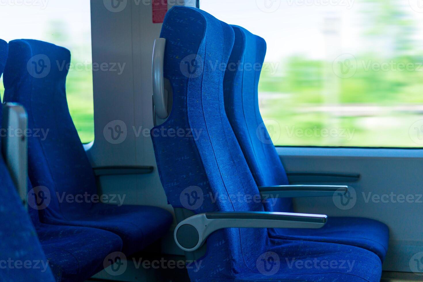 interior of commuter passenger train car, row of chairs and a motion-blurred landscape outside the window photo