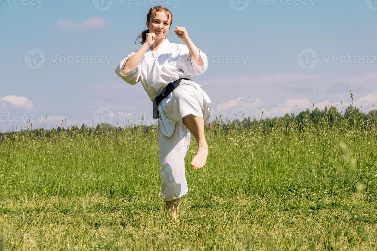 teenage girl training karate kata outdoors, prepares to yoko geri kick photo
