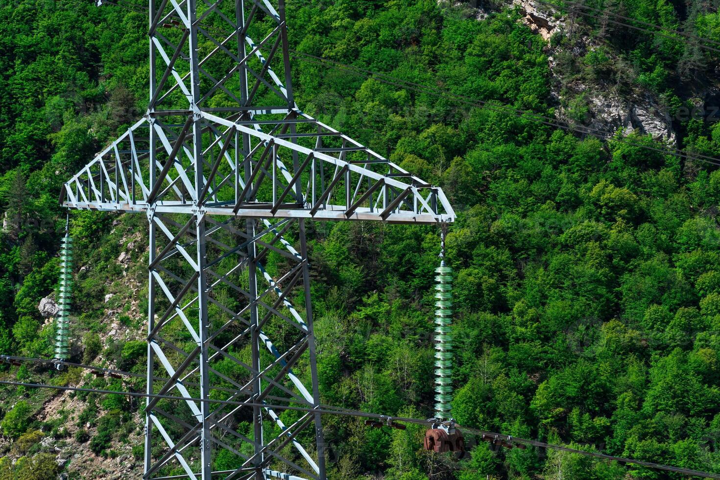 fragment of a power transmission pole close-up against the background of a wooded mountain slope photo