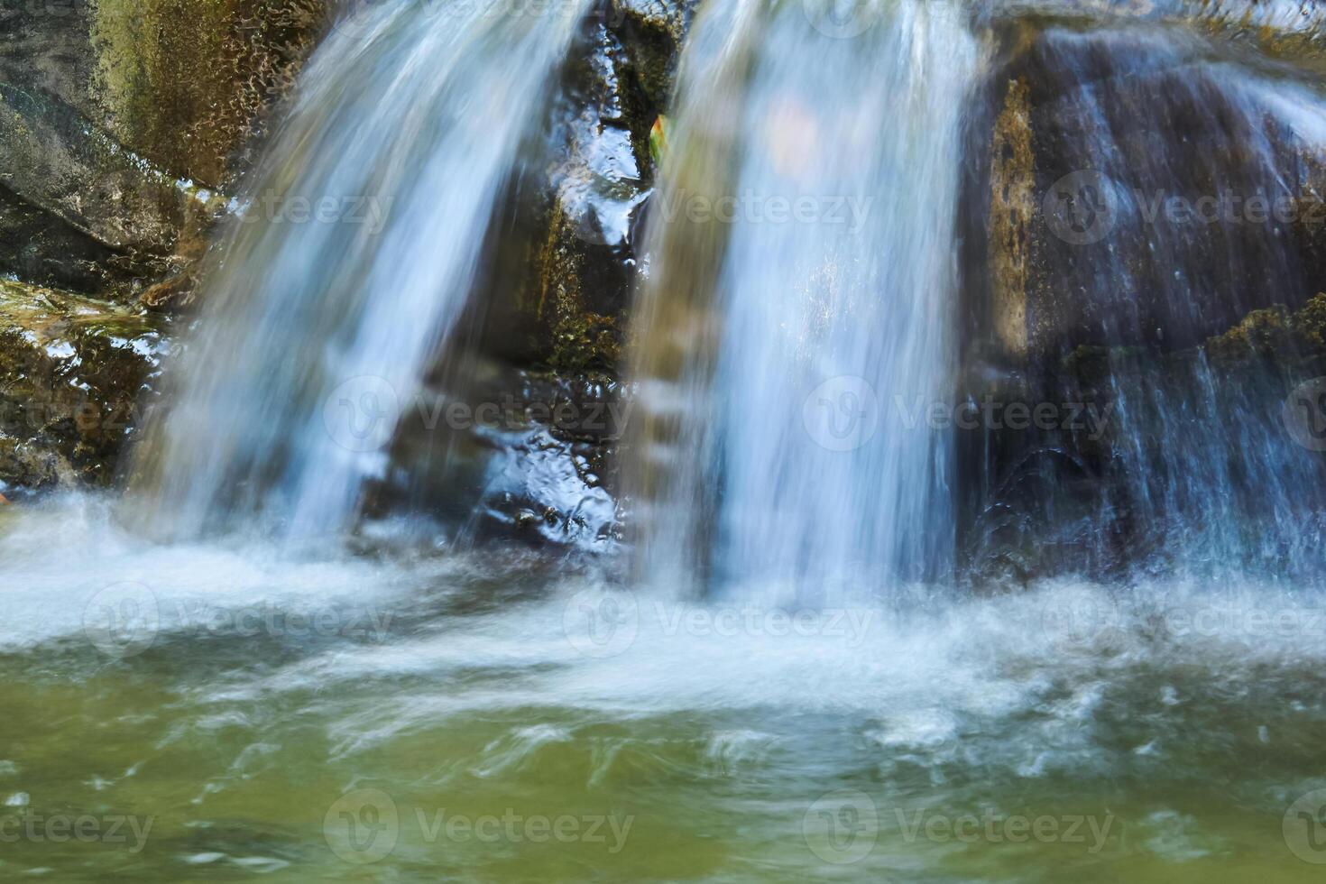 waterfall jets in a mountain stream between rocks, the water is blurred in motion photo